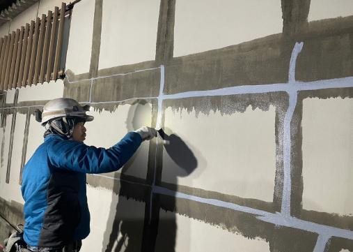 工場外壁のはく落防止工事で下地処理を行う様子